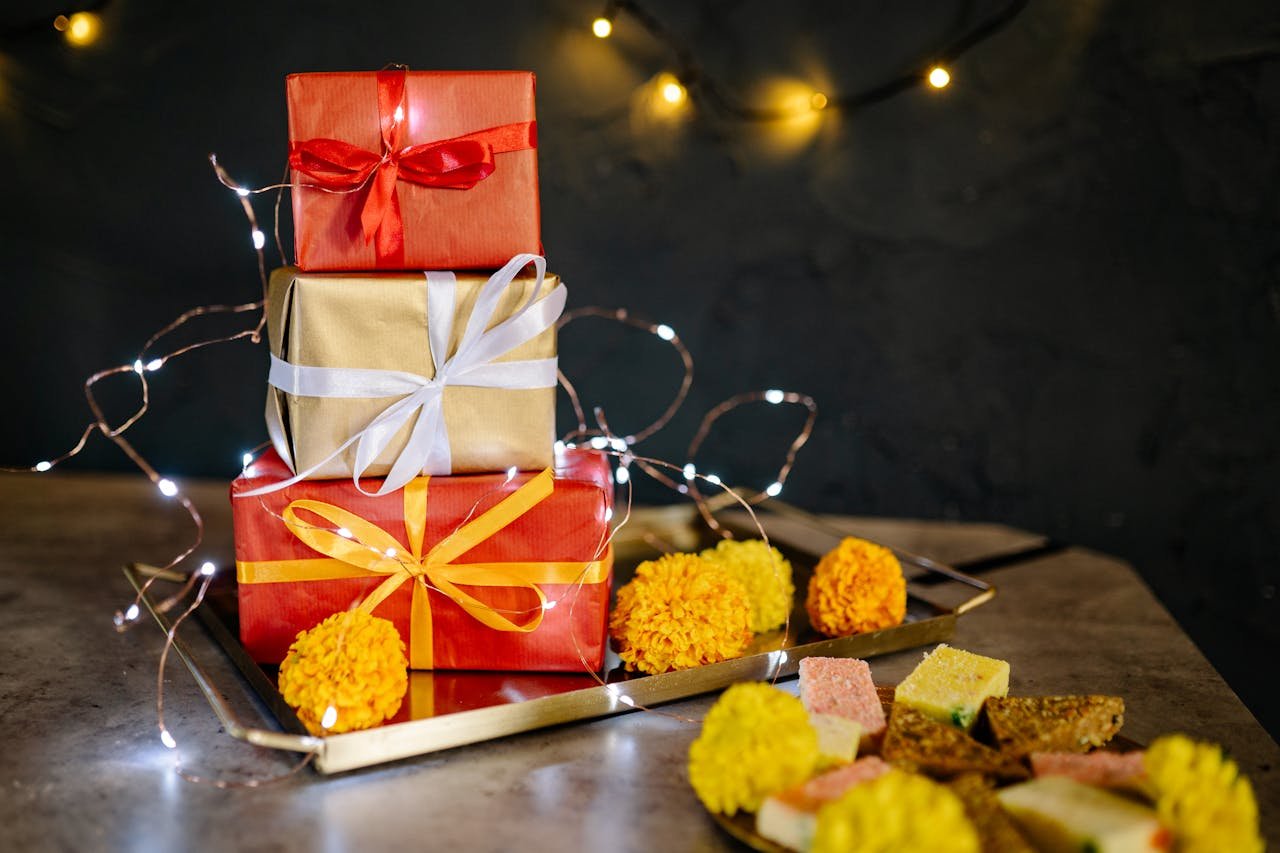 about-01 Colorful wrapped presents on a tray adorned with lights and marigold flowers for Diwali celebration.